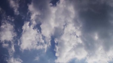 Mavi gökyüzünde hızla ilerleyen beyaz bulutların sinematik zaman atlaması bulutların kenarlarında parlayan parlak güneş ışınlarıyla