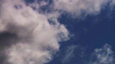 Beyaz tüylü kümülüs bulutları açık bir günde açık mavi gökyüzünde süzülüyor. Yumuşak rüzgarlar ve barışçıl doğal atmosfer.