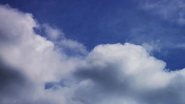 Açık ve güneşli bir yaz gününde, çerçevenin üzerinde pürüzsüz bir şekilde hareket eden kabarık beyaz bulutlarla parlak mavi bir arkaplan.