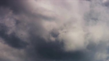Koyu beyaz ve koyu gri fırtına bulutları rüzgarlı ve değişen bir sonbahar gününde mavi gökyüzünde hızla hareket ediyor.