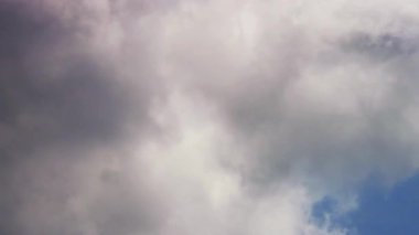 Hava ve hava akımlarının değiştiği açık bir günde mavi gökyüzünde hızla ilerleyen beyaz ve gri bulutlar.
