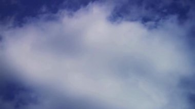 Derin mavi gökyüzünde hareket eden ince beyaz bulutlar bir doğa arka planı videosu için sakin ve huzurlu bir atmosfer yaratıyor.