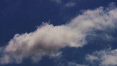 İnce beyaz bulutlar ve koyu gri fırtına bulutları ilkbaharda rüzgarlı bir öğleden sonra derin mavi gökyüzünde hareket ederler.