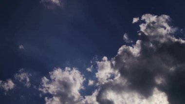 Güzel güneş ışınları, dramatik bir günbatımında ya da gün doğumunda, derin mavi bir gökyüzünde, karanlık bulutları delip geçer.