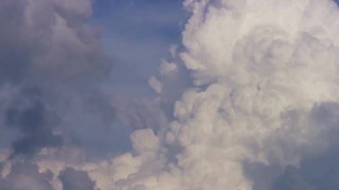 Doğal dünyada huzurlu bir günde canlı mavi bir gökyüzüne karşı hareket eden ve değişen büyük beyaz bulutlar.