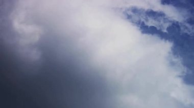 Havanın rüzgarlı olduğu bir günde gökyüzünde hızla dönen ve hareket eden beyaz ve gri bulutların yakın görüntüsü