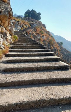 Uzun dik beton merdivenler, engebeli yamaçlar.