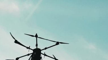 Parlak turkuaz gökyüzüne karşı alçak açılı altıgen dron silueti