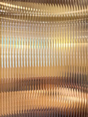 Flütlü camların veya çizgili camların, altın arka planların kırılması ve arkasında sarı ışıkların kırılması ile yakın dokusu. Flütlü cam estetik açıdan güzeldir. Kusursuz arkaplan dokusu.