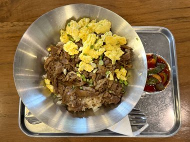 Yağda yumurta ve pirinçle doğranmış bifteği kapat. Soya soslu ve tava tabağı ahşap masada servis edilen tipik bir Asya yemeği. Yemek fotoğrafçılığı