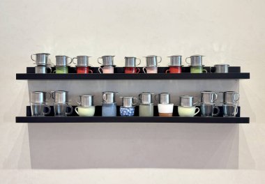 Beyaz duvarda izole edilmiş, raflarda ve çıkıntılarda serili küçük sos kupaları ya da soslu tekne sürahileri..