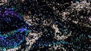 Renkli kum ve dalgaların dalgalı yönleriyle rastgele aktığı parlak kum taneciklerini oynayan interaktif ekran görüntüsü. Lider ışıklar, modern teknoloji. Mavi, siyah ve beyaz renkte..