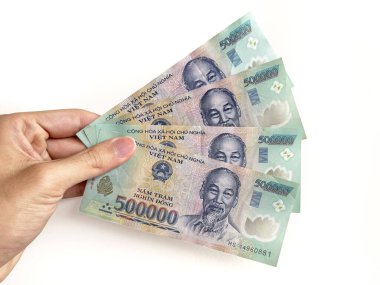 500.000 nominal değerde Vietnamlı dong banknotlarını tutan bir elin yakınına. Dong, Vietnam 'ın ulusal para birimi ve para birimi kodu VND. Beyaz bir arkaplanda izole edilmiş