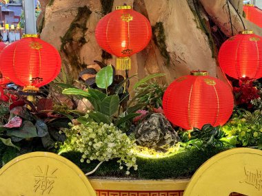 Aydınlatılmış kırmızı fener, oryantal bonsai ağaçları, dev altın sikkeler ve çalılarla Çin yeni yıl süslemeleri. Çince karakter Fu Means Blessing 'i heceler. Mutlu Çin Yeni Yılı