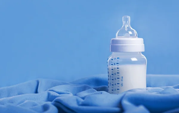 Baby milk bottle on a blue sheet — Stock Photo, Image