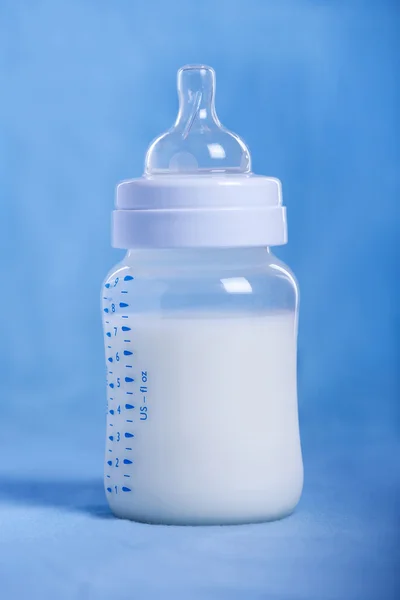 Бутылочка с молоком на синей простыне Стоковое Фото