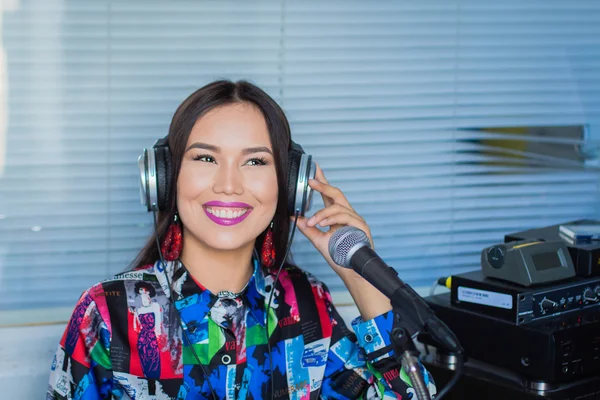 Girl in headphones with a microphone on the radio in the studio — Stock Photo, Image