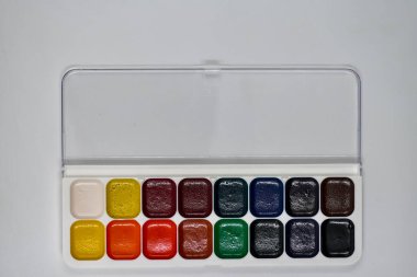 Beyaz arkaplanda suluboya boyaları aç, düz yatay fotoğraf, çok renkli suluboya resimler.