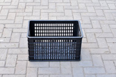 Tarımsal ürünleri toplamak ve depolamak için arka bahçede duran boş bir siyah plastik kutu..