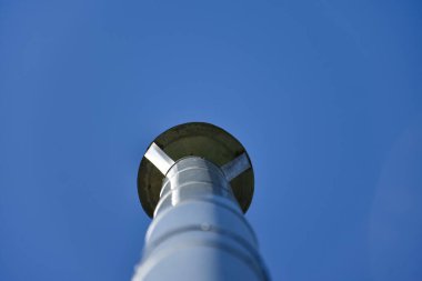 Mavi gökyüzüne karşı evin çatısındaki galvanize baca.