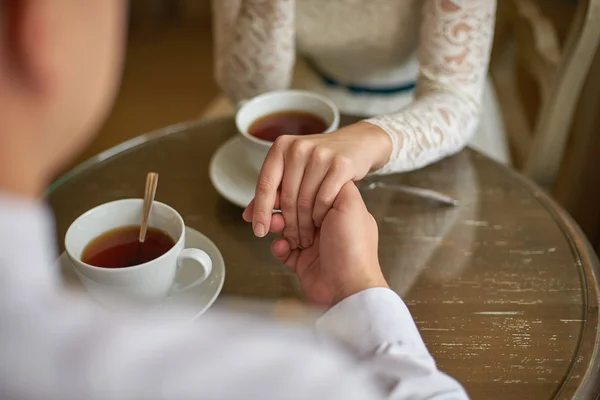 Couple holding hands at the table in a cafe for a cup of tea — Stock Photo, Image
