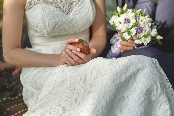 Mela rossa in mani della sposa in un vestito bianco — Foto Stock