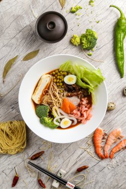 Deniz ürünleri, erişte ve beyaz bir tabakta sebze çorbası