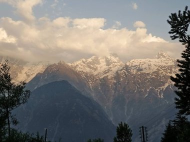 Gün batımından önce akşam saatlerinde güneş ışığıyla kaplı güzel karlı dağlar.