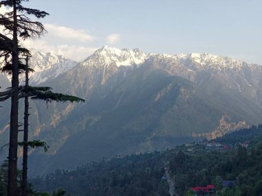 Gün batımından önce akşam saatlerinde güneş ışığıyla kaplı güzel karlı dağlar.