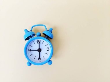 Sarı arka planda mavi alarmlı saat. Zaman yönetimi ve planlama kavramı