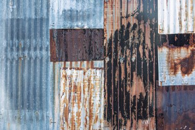 Gri, koyu kahverengi ve açık kahverengi gibi çeşitli renklerde paslanmış kıvrımlı metaller bir duvar oluşturmak için bir araya getirilir. Ayrıntılı kısayol yönelimi için resim kapatıldı.