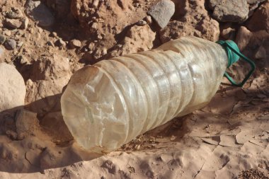 Çevresel bir sorun olan yerde duran plastik şişenin yakın plan çekimi.