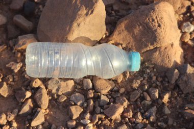 Yerde yatan plastik bir şişe, plastik kirlilik, plastik çevresel etki.