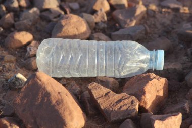 Yerde yatan plastik bir şişe, plastik kirlilik, plastik çevresel etki.