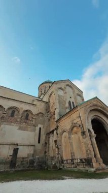Kutaisi, Georgia 'daki Bagrati Katedrali' nin etrafında kuşlar uçuşuyor. Güneş parlıyor ve bulutlar tepemizde sürükleniyor. Tarihi yapı dikkat çekiyor..