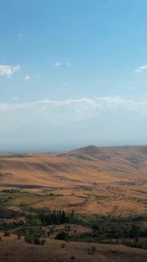 Görüş mesafesi Ararat Dağı 'nı gösteriyor. Etrafı sislerle çevrili. Tepeler ve tarlalar parlak bir gökyüzünün altında..