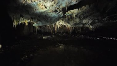 Bir grup, eşsiz kaya oluşumlarını ve akan suyu gözlemlemek için karanlık bir mağaraya girer. Çevre gizemli ve doğal harikalarla dolu..