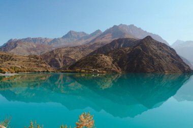 Sakin bir turkuaz göl etrafındaki yüksek dağları yansıtarak çarpıcı bir manzara yaratır. Sakin su ve berrak gökyüzü, doğada rahatlamaya ve tefekküre yol açar..
