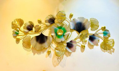 Zarif Metalik Ginkgo Yaprak Duvar Heykeli. Duvardaki sarı çiçek.