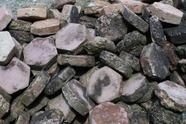 Düzensiz, desenli kaldırım taşları yığınının yakın plan resmi açık hava yolları, bahçe dekorasyonu veya peyzaj tasarımı için uygun, doğal taş çeşitliliği ve engebeli yüzey detayları sergileniyor..