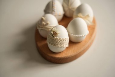 Çeşitli dekorasyonlara sahip bir Paskalya yumurtası koleksiyonu ahşap bir tepsinin üzerinde düzgünce duruyor. Her yumurta, doğal elementler ve kurdeleler kullanılarak eşsiz detaylar içerir..