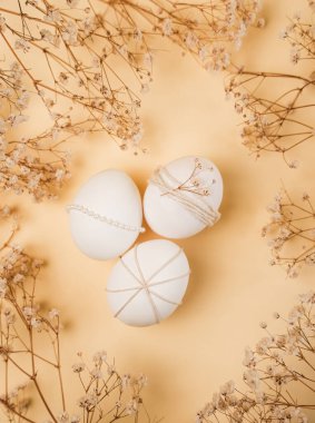 Üç beyaz yumurta süslenir ve sarı arka plana yerleştirilir. Kurumuş çiçekler yumurtaların etrafını sarar. Bu sahne Paskalya 'da geçiyor..