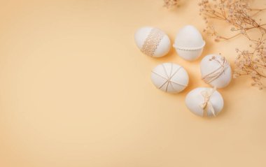 Paskalya yumurtaları iplerle ve dantellerle süslenir. Hafif bir arkaplanda düzenlenmişler. Kurumuş çiçekler bahar kutlamalarına biraz doğa katar..