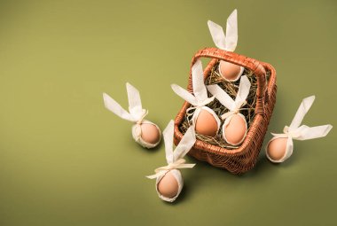 Paskalya yumurtaları bir sepete konur, tavşan kulaklarıyla süslenir ve samanların üzerinde dinlenir. Bazı yumurtalar sepetin etrafına sade yeşil bir yüzeye yerleştirilir..