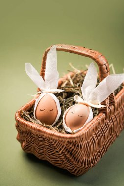 Sahne dekoratif Paskalya yumurtalarını gösteriyor. Çimlerle dolu bir sepetin içine yerleştirilmiş tavşanlar olarak dizayn edilmiş. Arka plan koyu yeşil renkte, yumurtalara vurgu yapıyor..