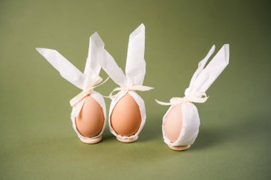 Üç yumurta beyaz kağıda sarılır ve tavşan kulakları kurdeleyle bağlanır. Ayar parlak ve neşeli, Paskalya kutlamalarının ve geleneklerin ruhunu yansıtıyor..