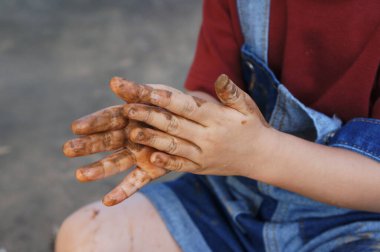 Bir çocuğun elleri çamurla kaplı, oynuyor ve keşfediyor.