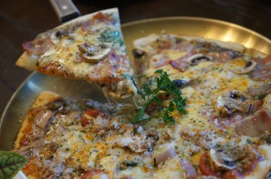 Lezzetli bir pizza dilimi bütün pizzadan alınıyor, dokularını ve malzemelerini yakalıyor, tadını çıkarmaya hazır.