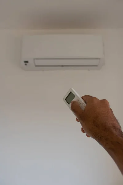 Holding remote control air conditioner on blurred background living room.
