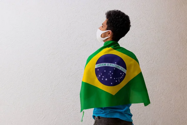 白い上に隔離されたブラジルの旗を保持している流行のマスクを持つ黒人 — ストック写真